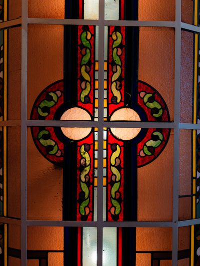 Detail van het glas-in-loodraam van het café met een art-decopatroon in groen, rood en amber.