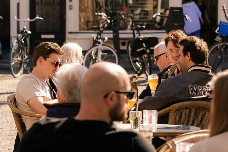 Een vol terras met gasten in de voorjaarszon.